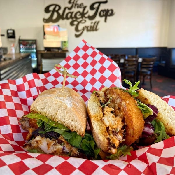 Two Blacktop Grill street food sandwiches with lettuce and meat, served in a red and white checkered basket.