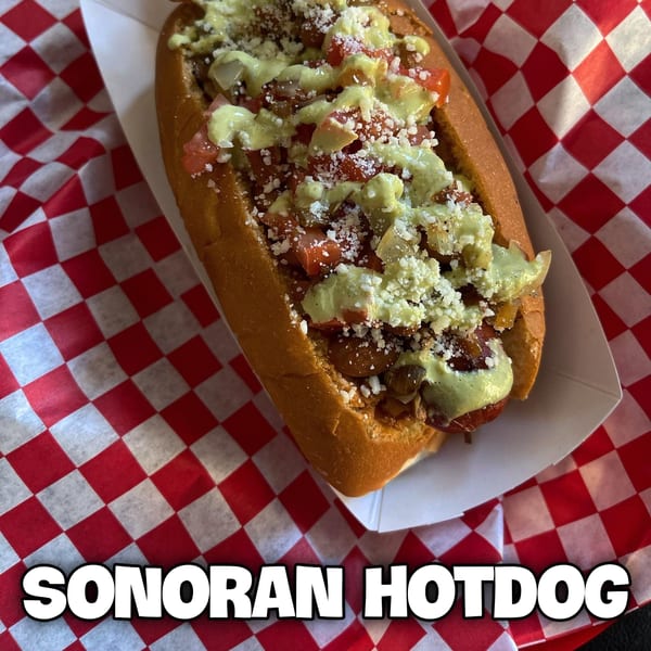 A Sonoran hotdog from The Blacktop Grill, topped with avocado sauce, diced tomatoes, and cheese.