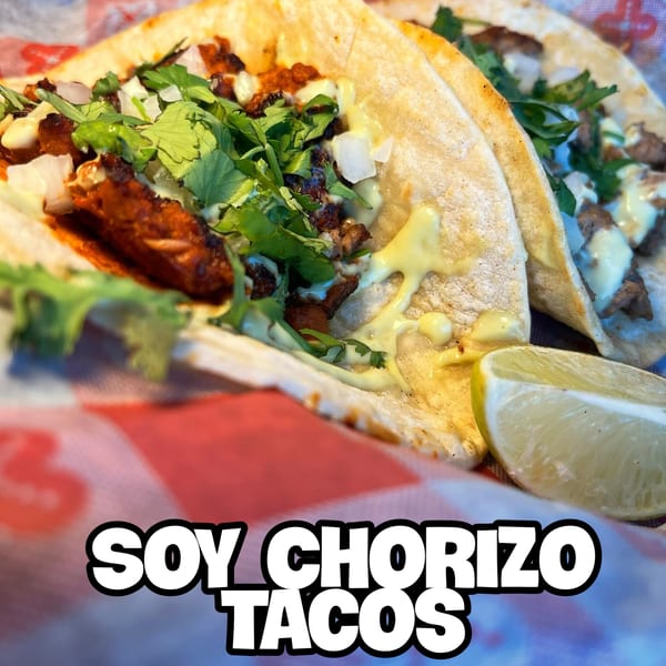 Close-up of two Blacktop Grill soy chorizo tacos with cilantro, onions, and lime.