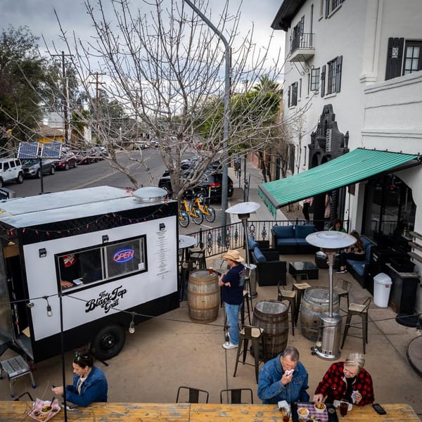 Overhead view of a food truck, outdoor patio seating, and people eating at tables.